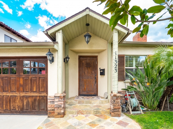 Front view of a house property with wide wooden door and flowers in 11323 Valley Spring Lane