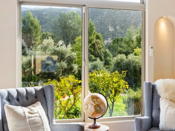 Living room side view with a globe, armchair and window view at 2175 Cold Canyon Road Calabasas