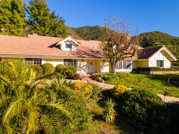 24592 Mulholland Highway - Beautiful house with a yellow and green garden in the front yard, featuring colorful flowers and well-maintained landscaping